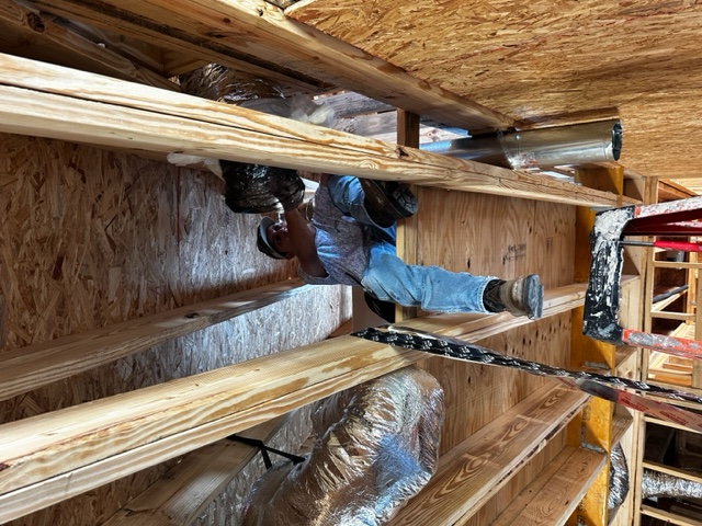 Technician installing ductwork in a new construction attic